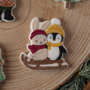 Hase und Pinguin im Schlitten
